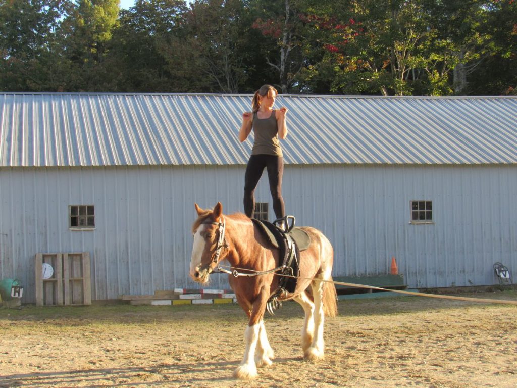 Aurora Vaulters coach and vaulter Cynthia Andrews demonstrates some of the compulsory exercises atop 13-year-Rosie. Deb Andrews (not visible) directs the Shire mare in a giant circle at the East Lamoine farm. Ellsworth American Photo by Maxwell Hauptman Aurora Vaulters coach and vaulter Cynthia Andrews demonstrates some of the compulsory exercises atop 13-year-Rosie. Deb Andrews (not visible) directs the Shire mare in a giant circle at the East Lamoine farm. Ellsworth American Photo by Maxwell Hauptman